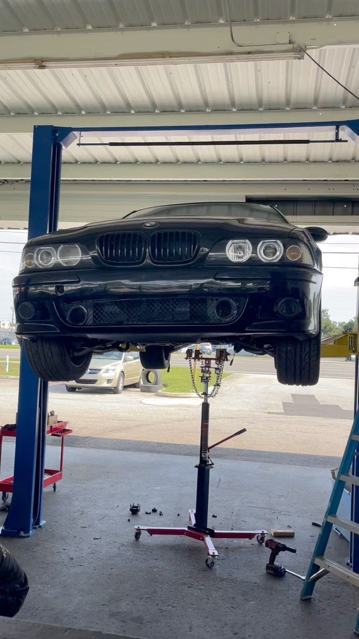 A black car is sitting on a lift in a garage.