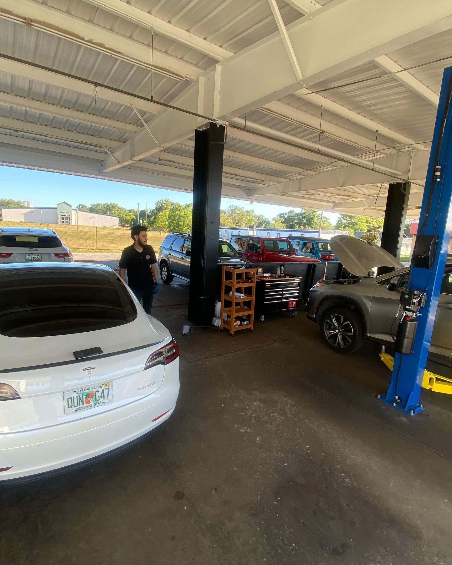 A man is standing next to a white car in a garage.