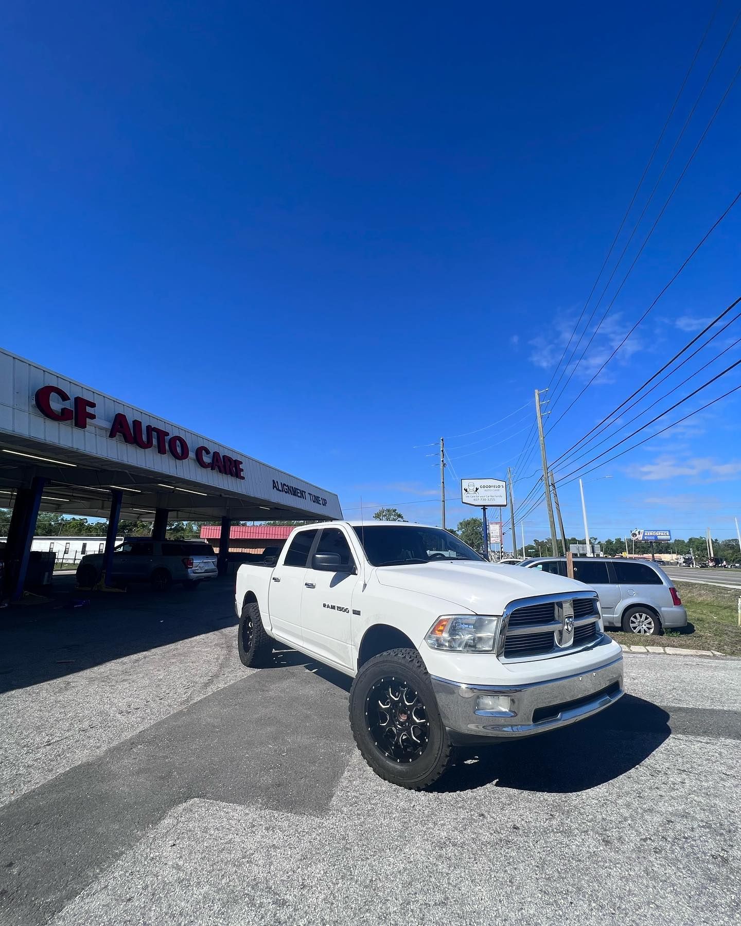 A white truck is parked in front of a car dealership.