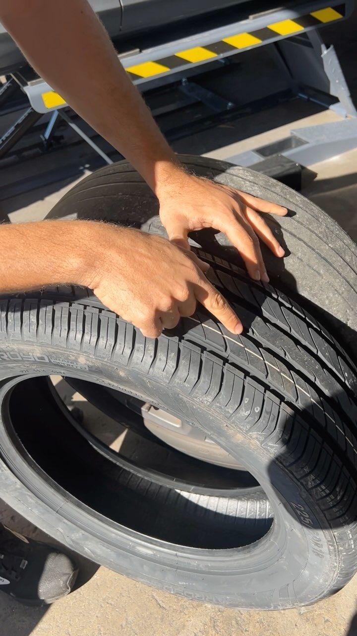 A person is pointing at a tire with their finger.