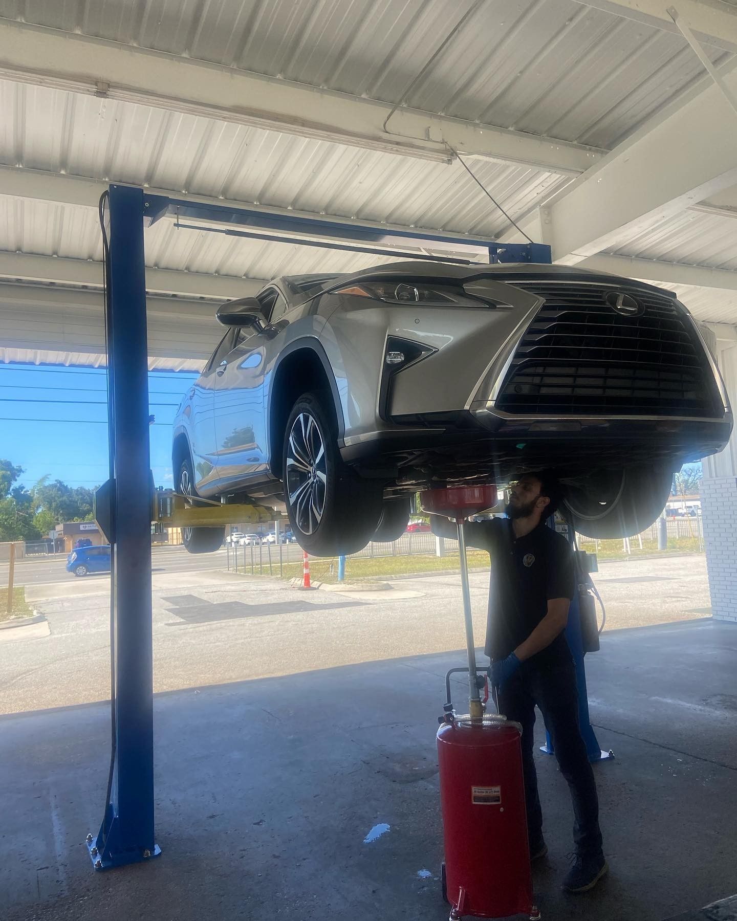 A man is standing next to a car on a lift.