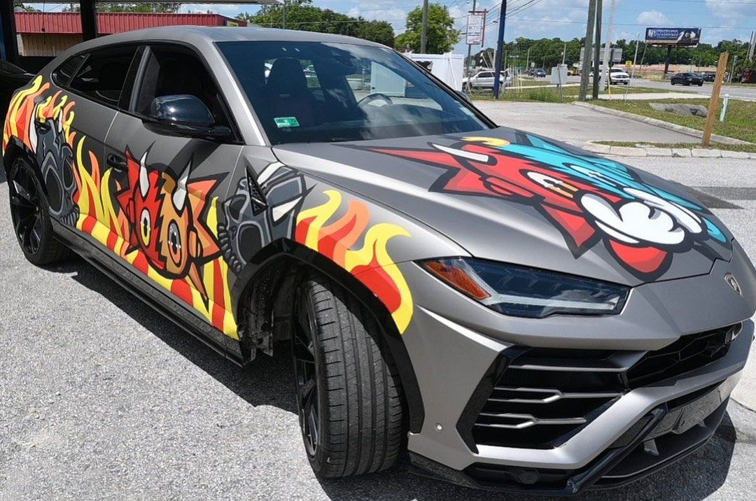 A car with graffiti on it is parked in a parking lot