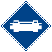 A blue diamond shaped sign with a white icon of a train