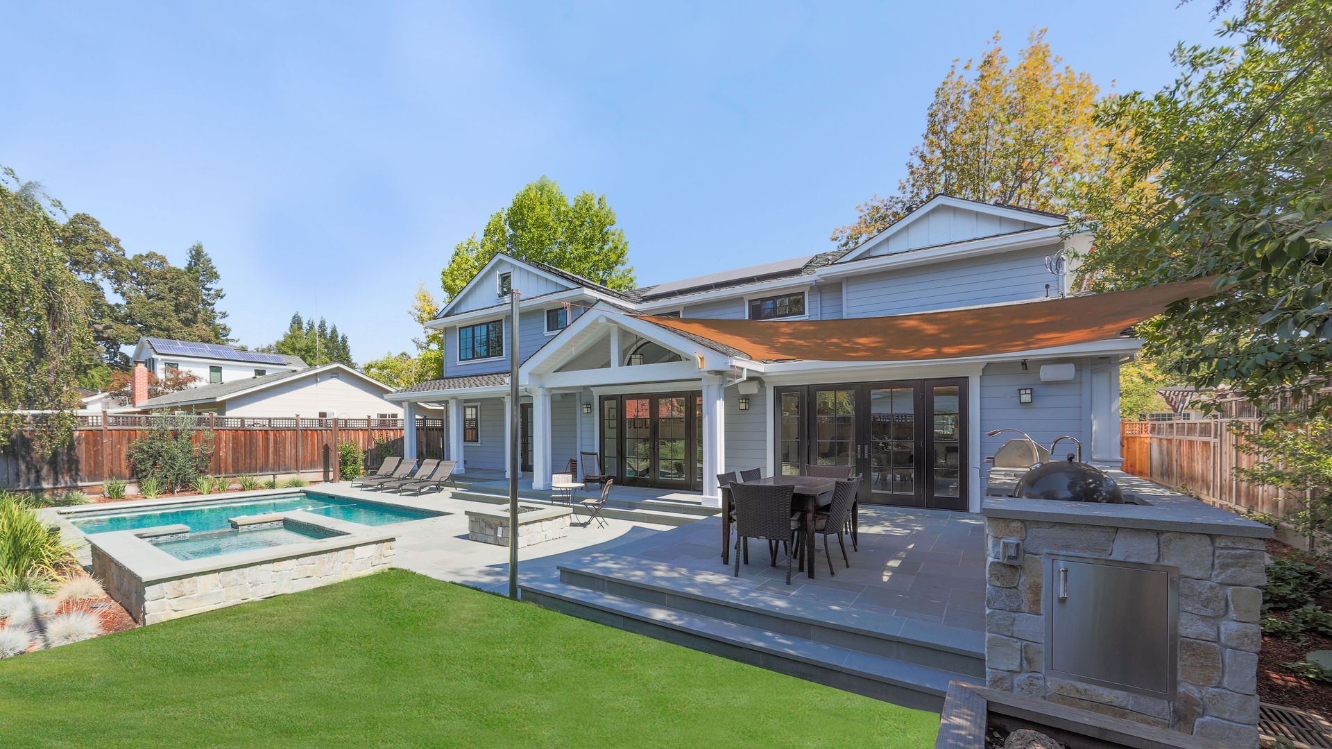 The backyard of a house with a swimming pool and patio area.