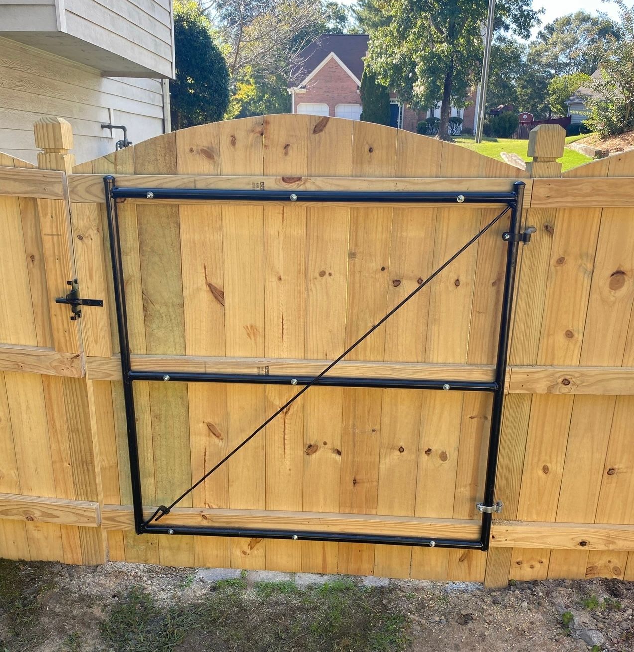 Wooden fence with black metal gate, diagonal support bar.