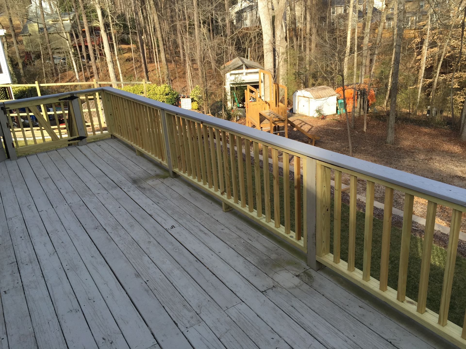 Wooden deck with newly built wooden railing overlooking a wooded backyard.