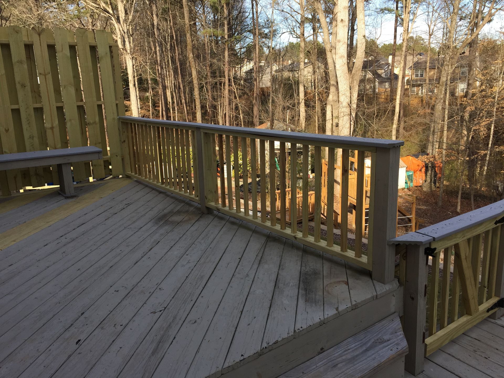 Wooden deck with railing overlooking a wooded area.