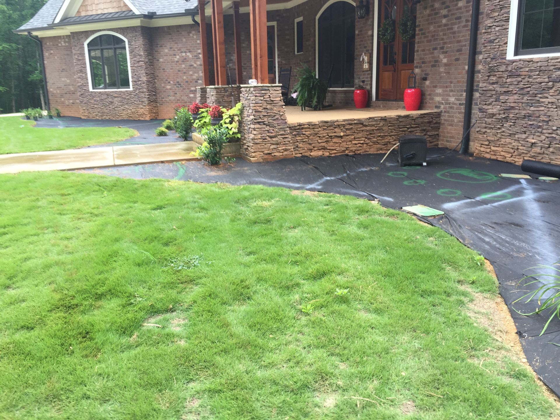 Green lawn leads to a house with a brick exterior and a porch.