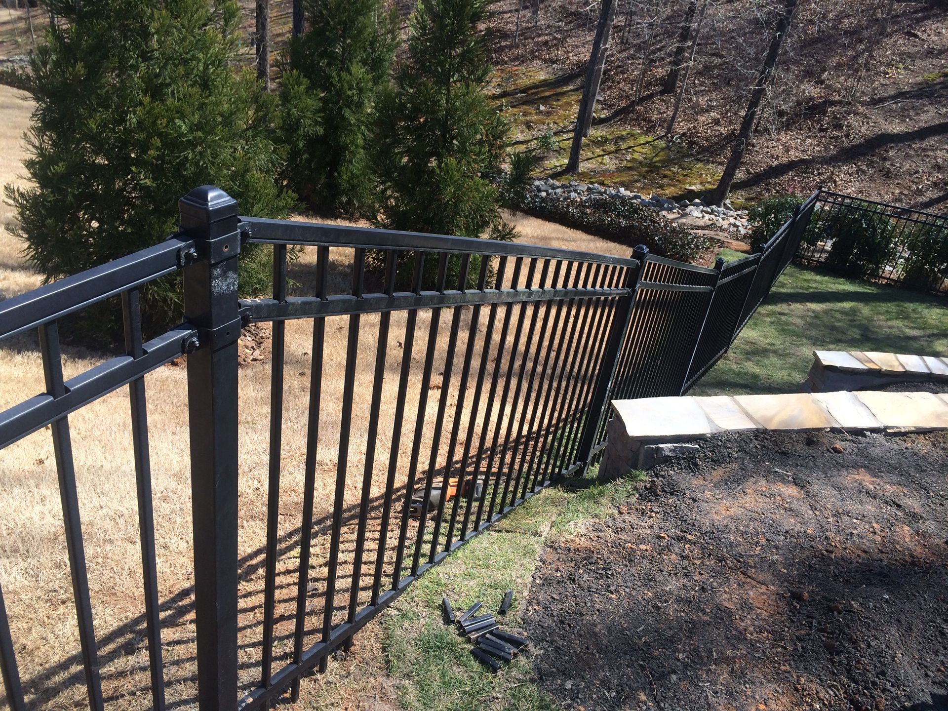 Black metal fence sloping down a hillside.