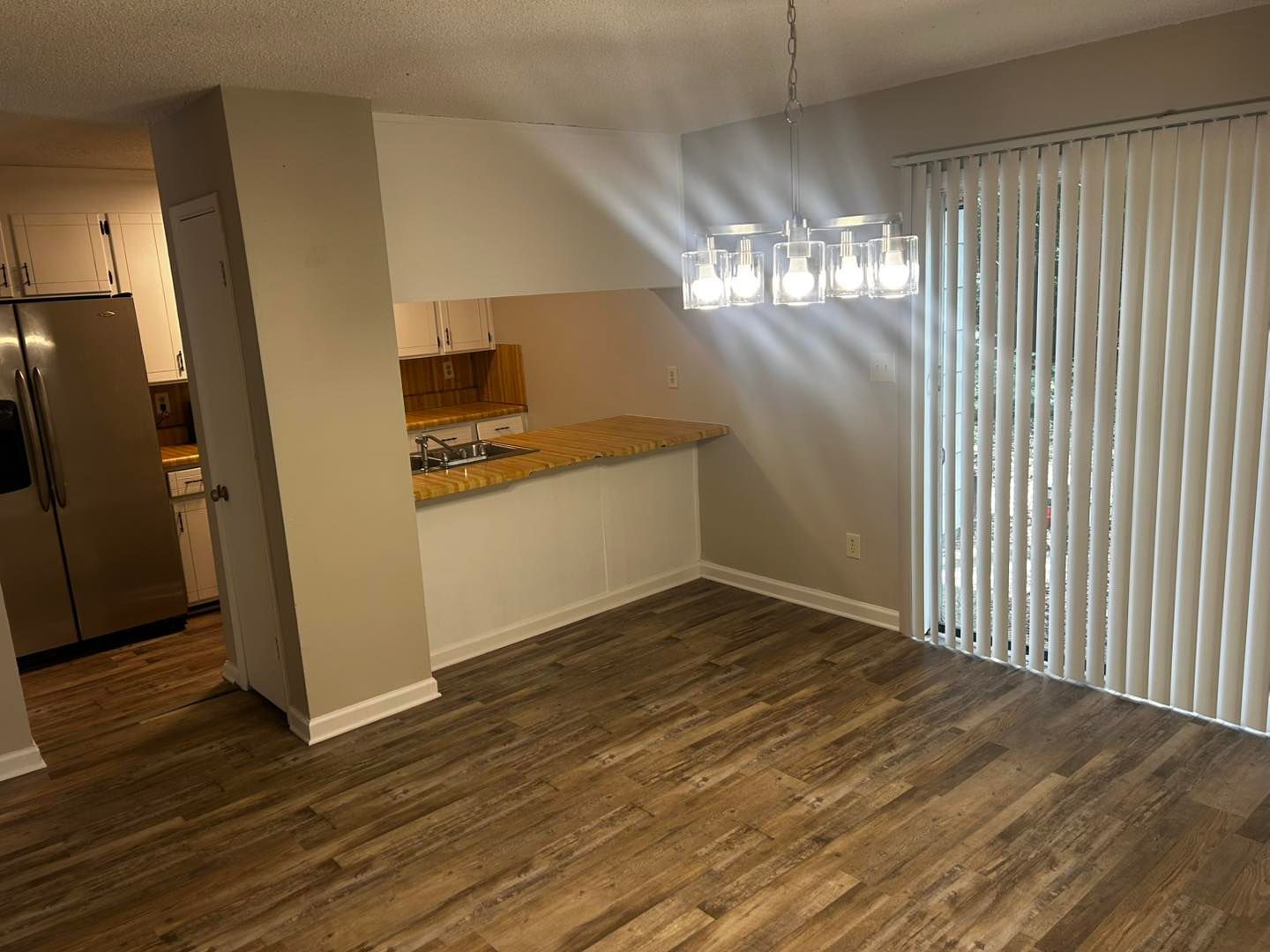 Dining area with wood-look floor, adjacent to a kitchen with granite countertop and sliding glass door.