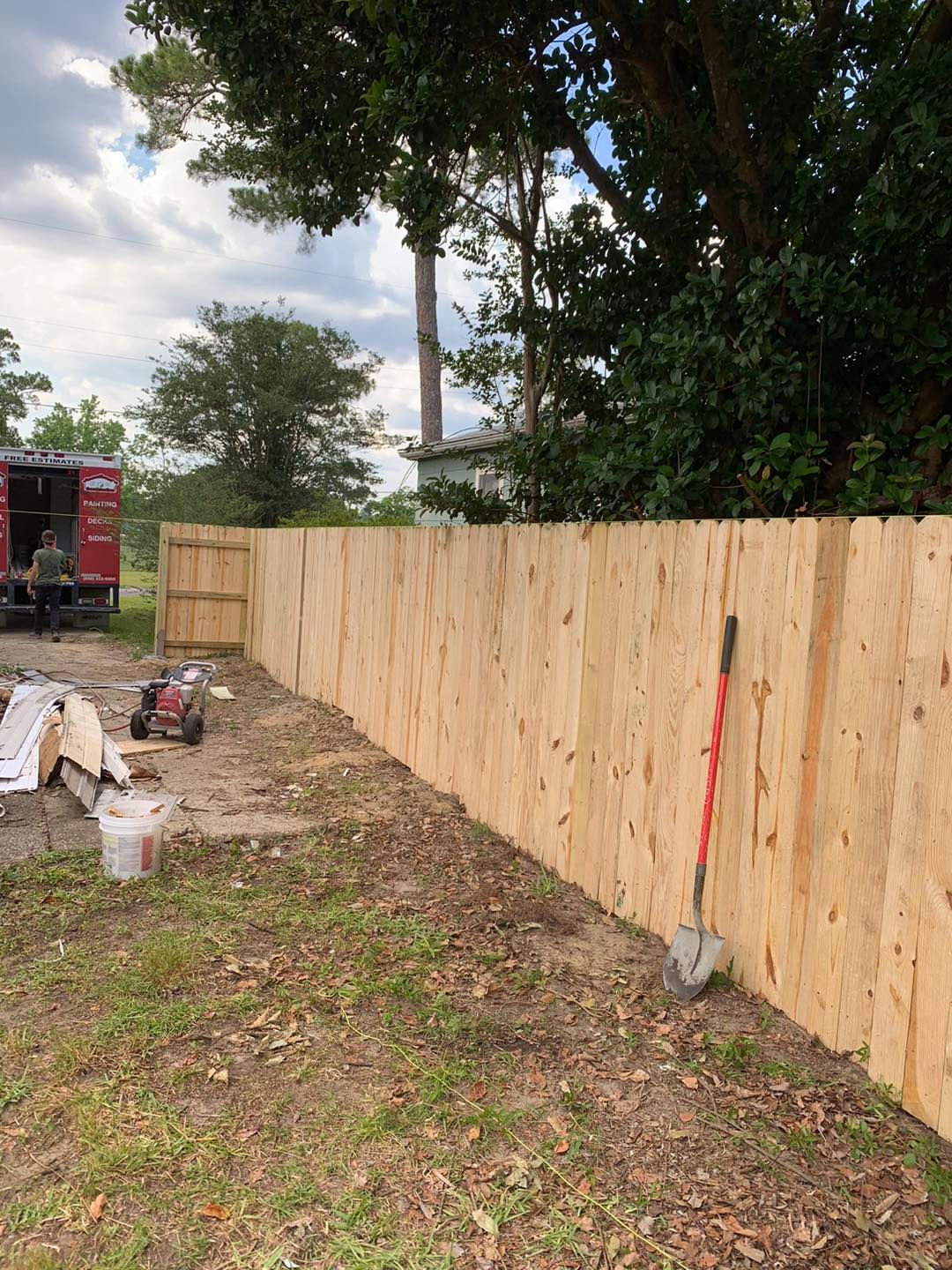 New plywood fence in a yard with construction tools and equipment.