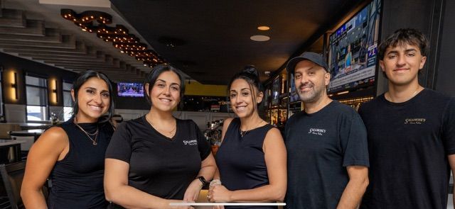 A man and a woman are standing next to each other in front of a bar.