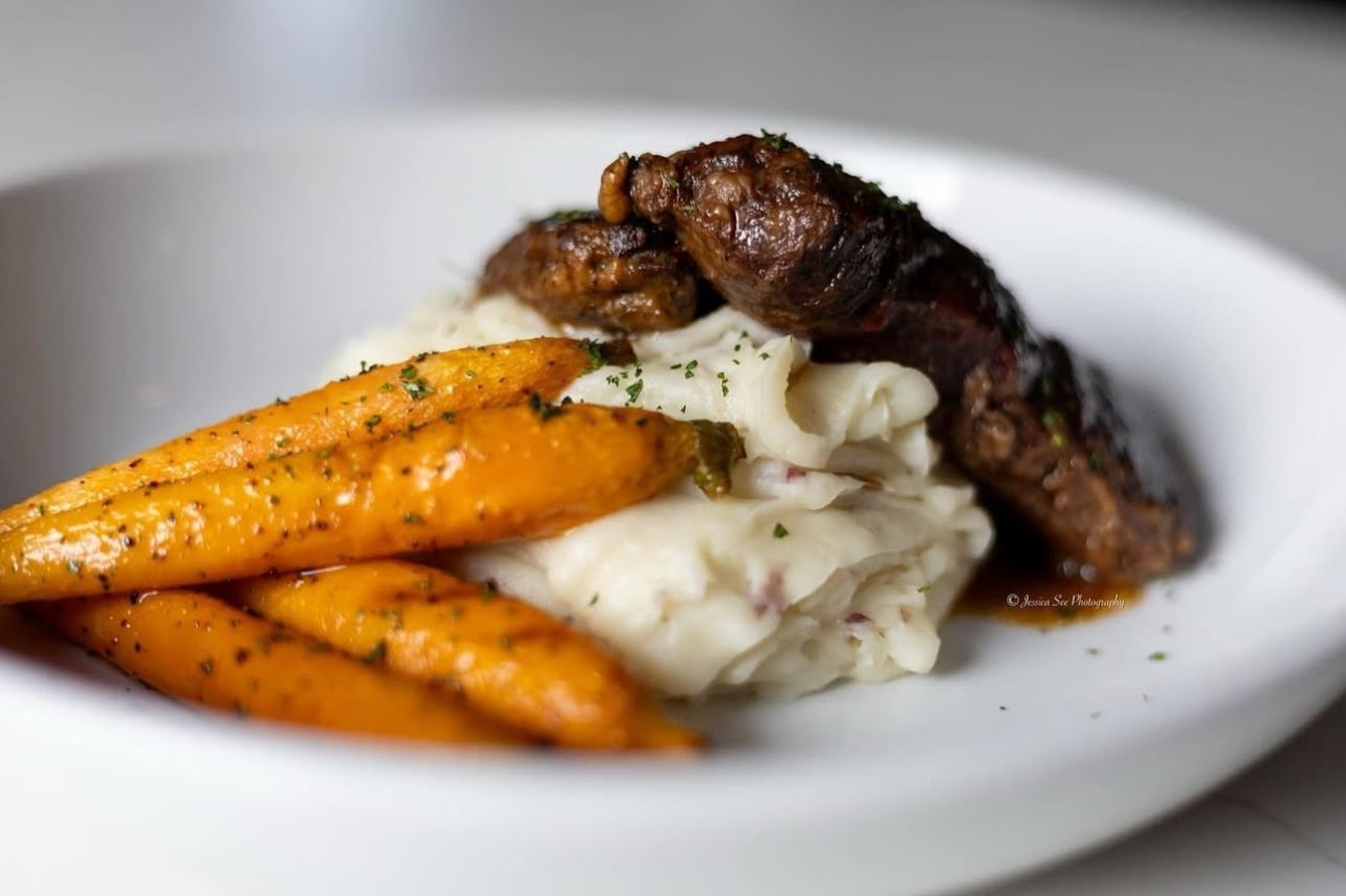 A white plate topped with carrots , mashed potatoes and meat.