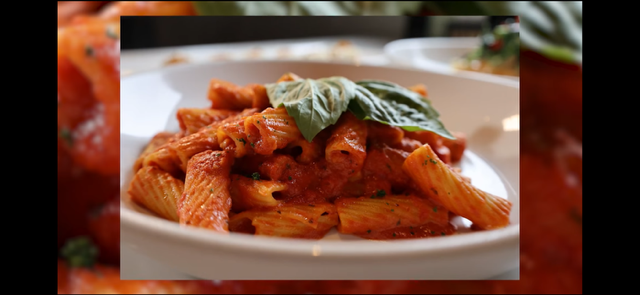 Pasta dish with tomato sauce and basil leaves on a white plate.