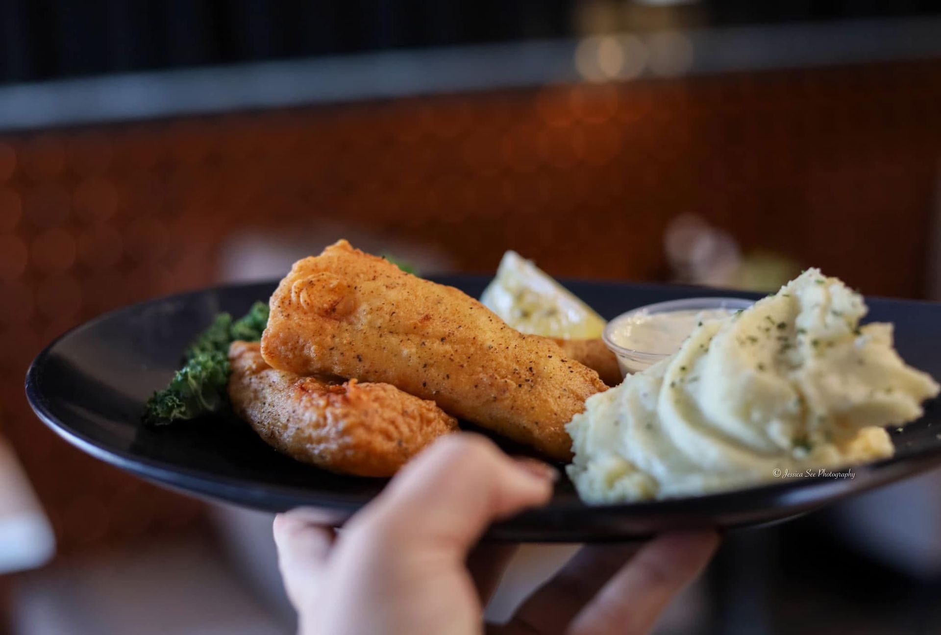 A person is holding a plate of food with mashed potatoes and broccoli