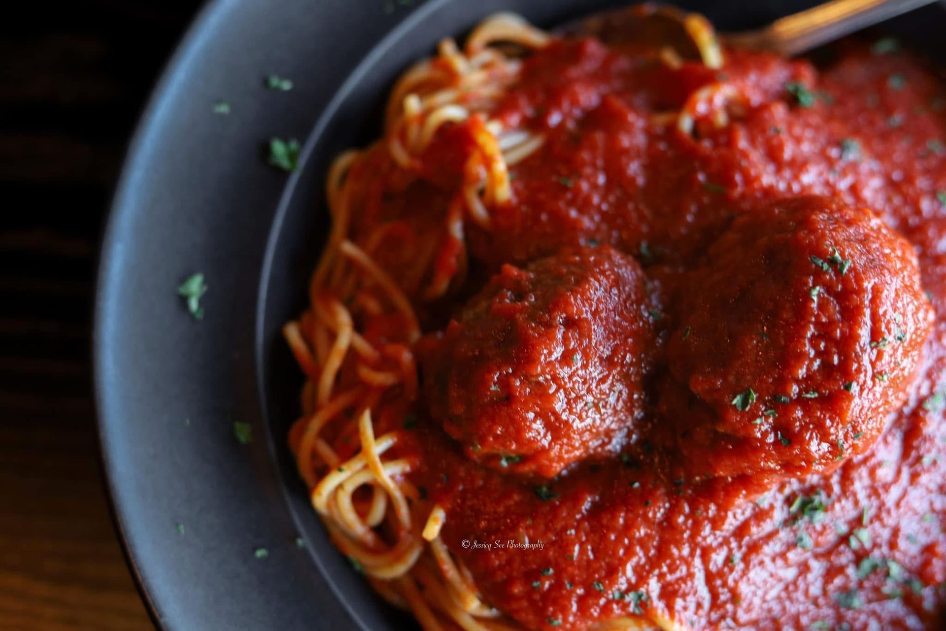 A close up of a plate of spaghetti and meatballs with sauce
