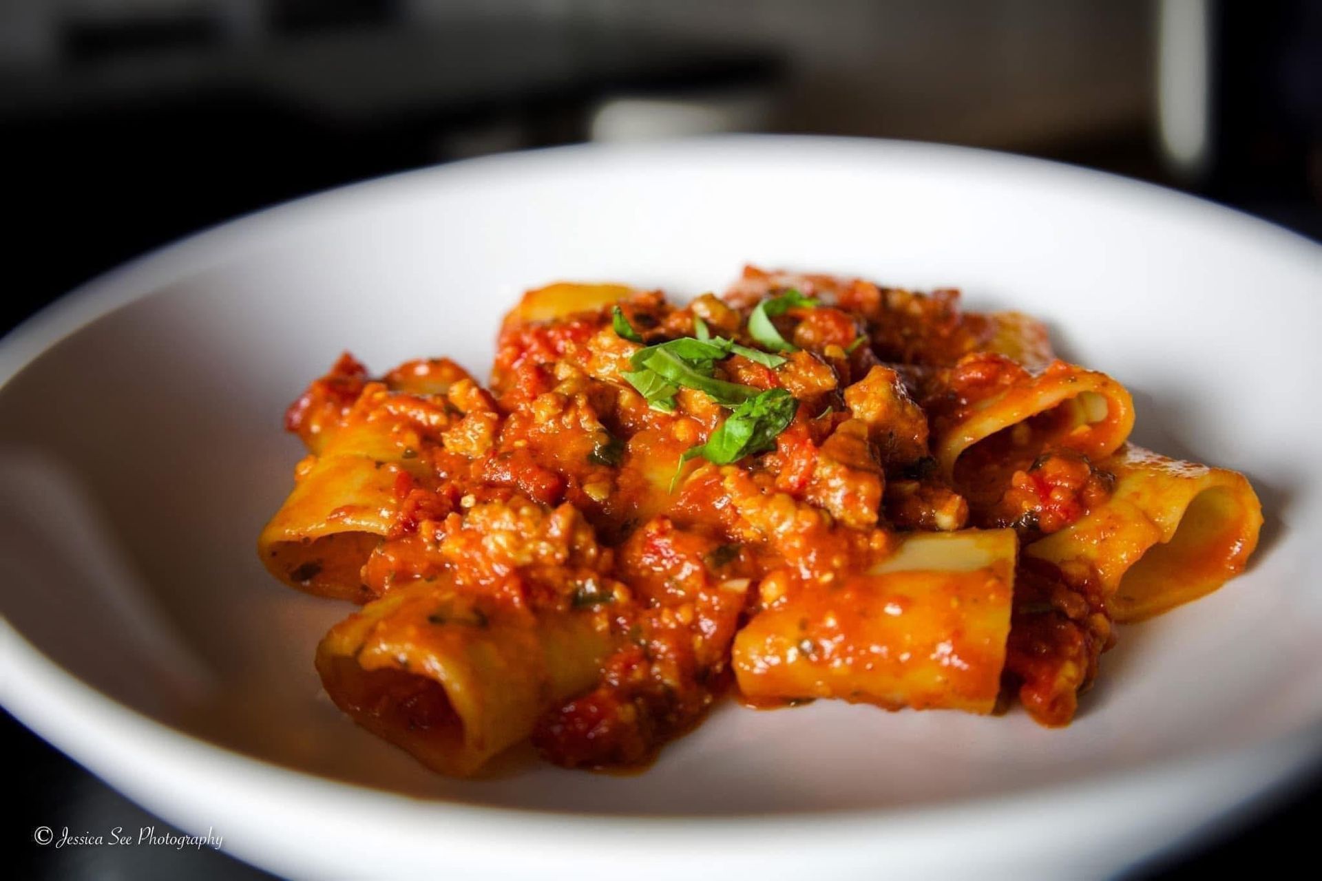 A white plate topped with pasta and tomato sauce