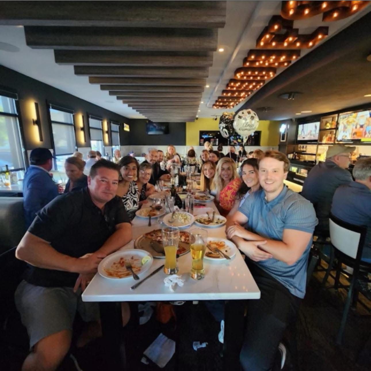 A group of people are sitting at a long table in a restaurant