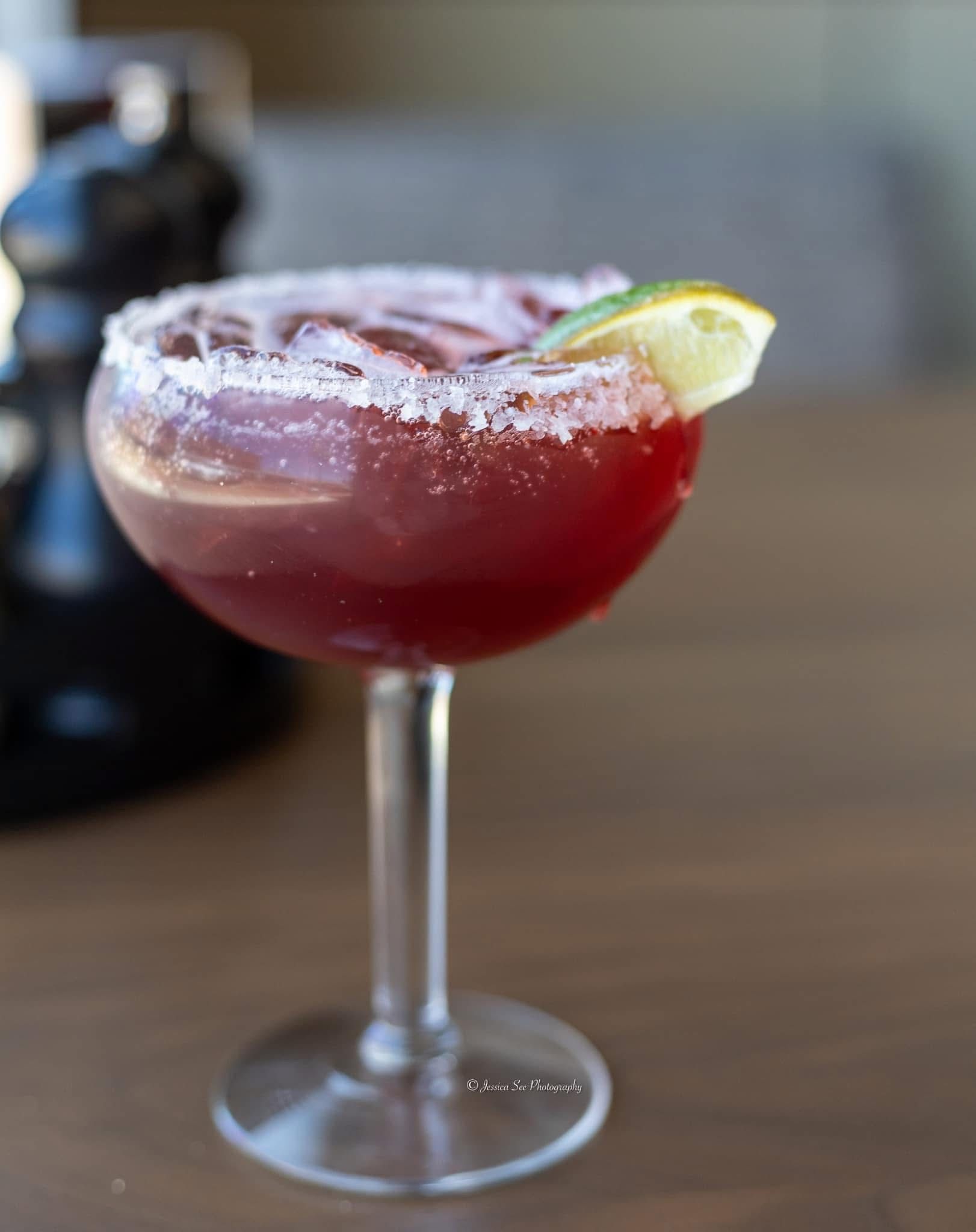 A close up of a red drink in a martini glass