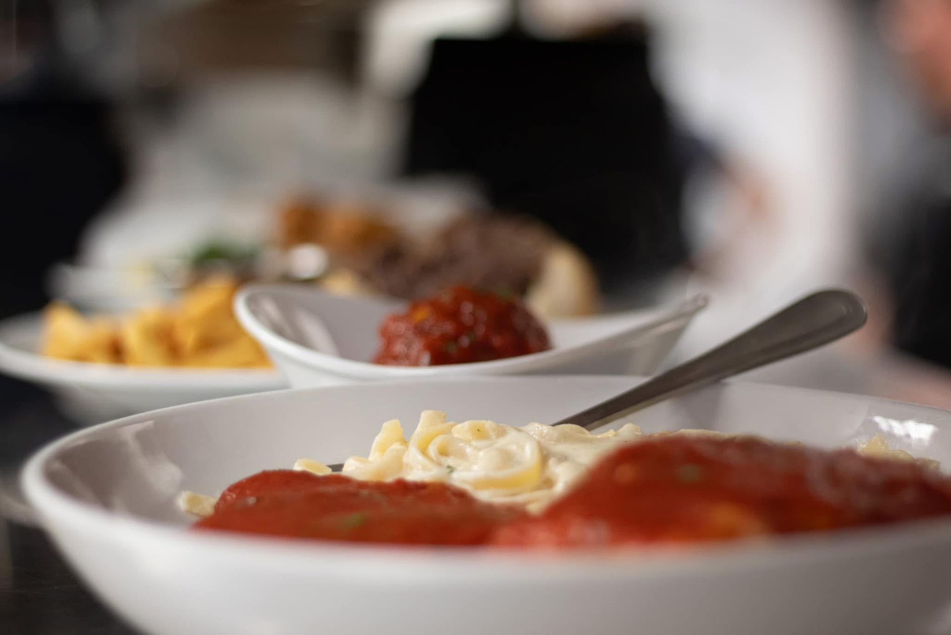 A close up of a bowl of pasta with sauce and a fork on a table