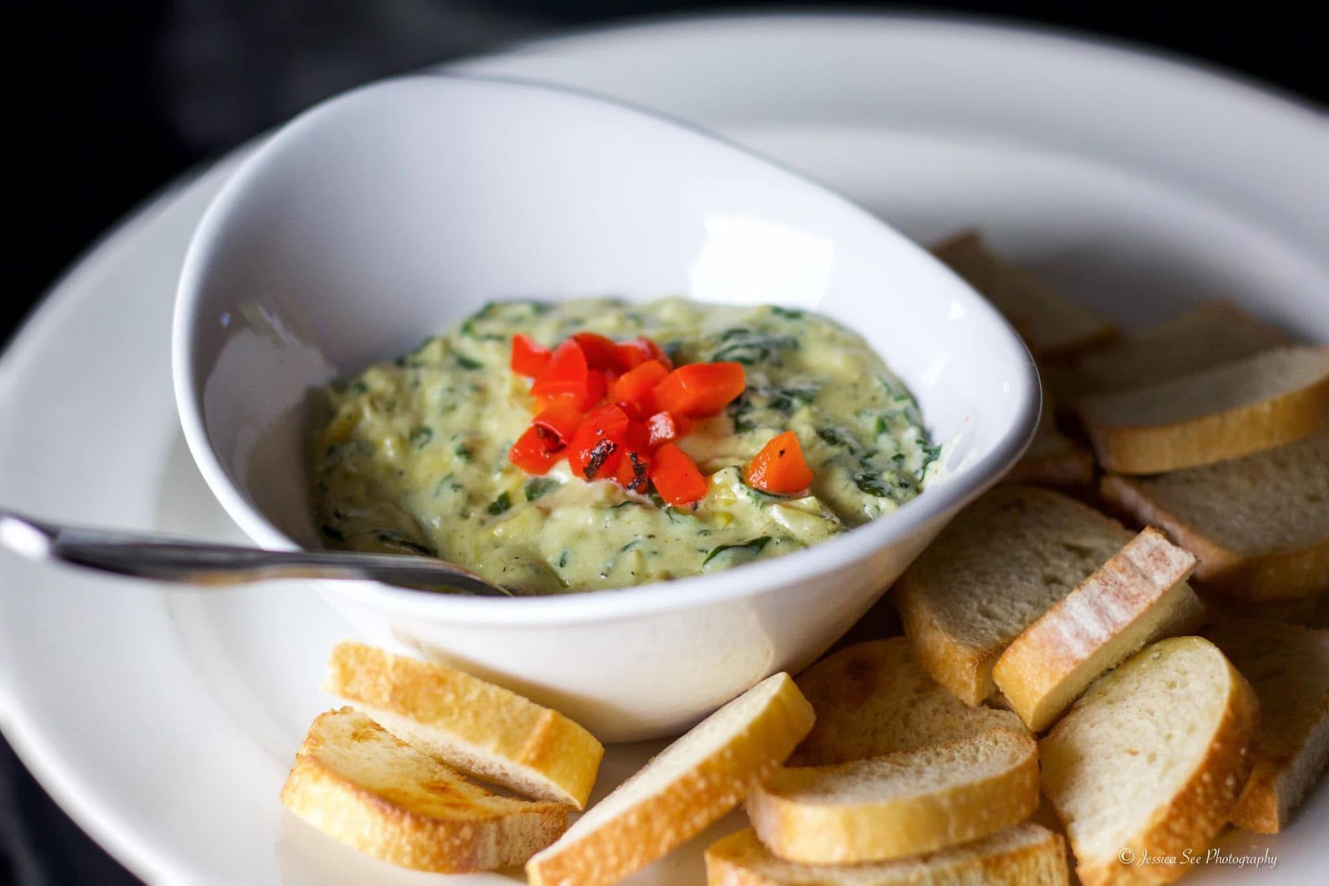 A white plate topped with slices of bread and a bowl of dip
