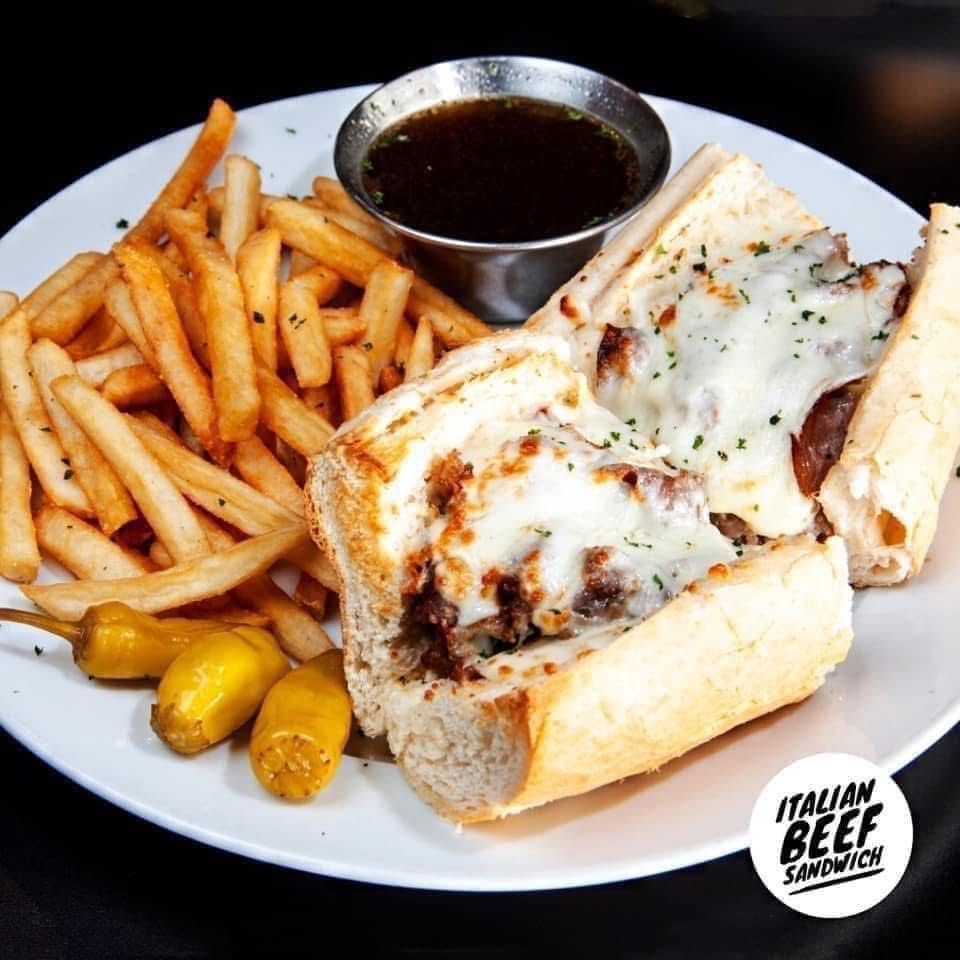 A white plate topped with an Italian sandwich and French fries
