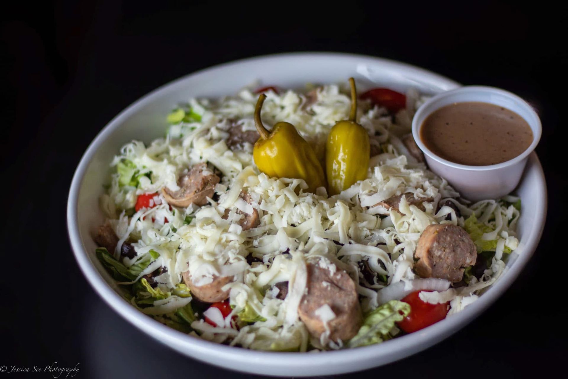A close up of a salad in a bowl with a dipping sauce