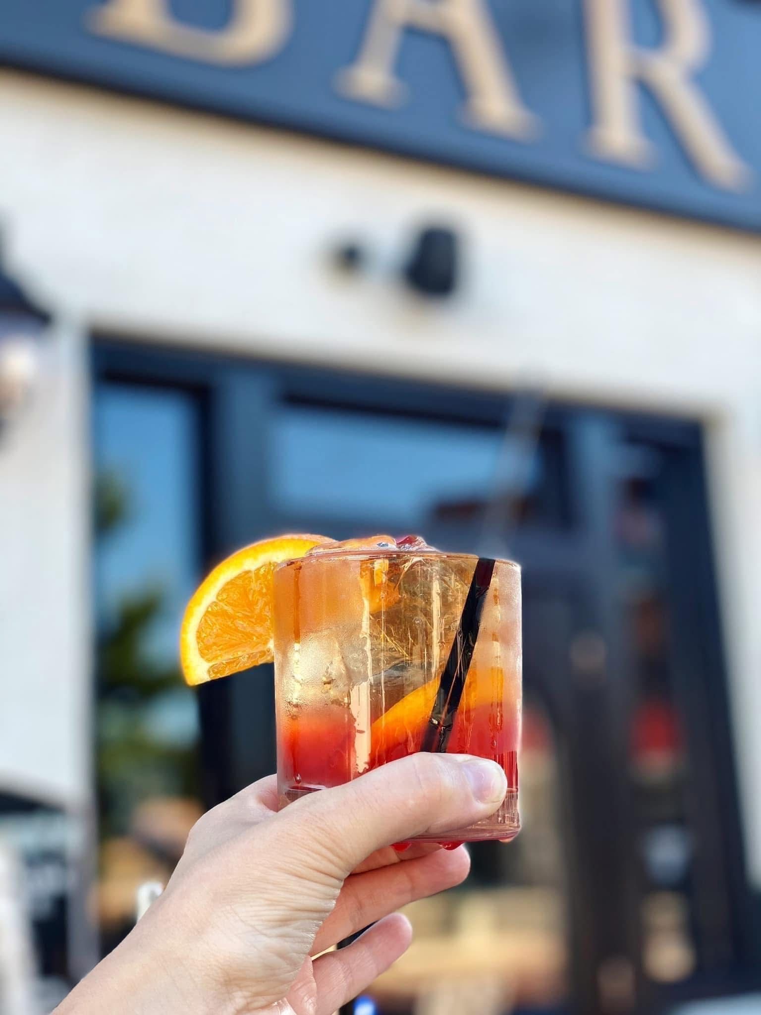 A person is holding a drink in front of a bar
