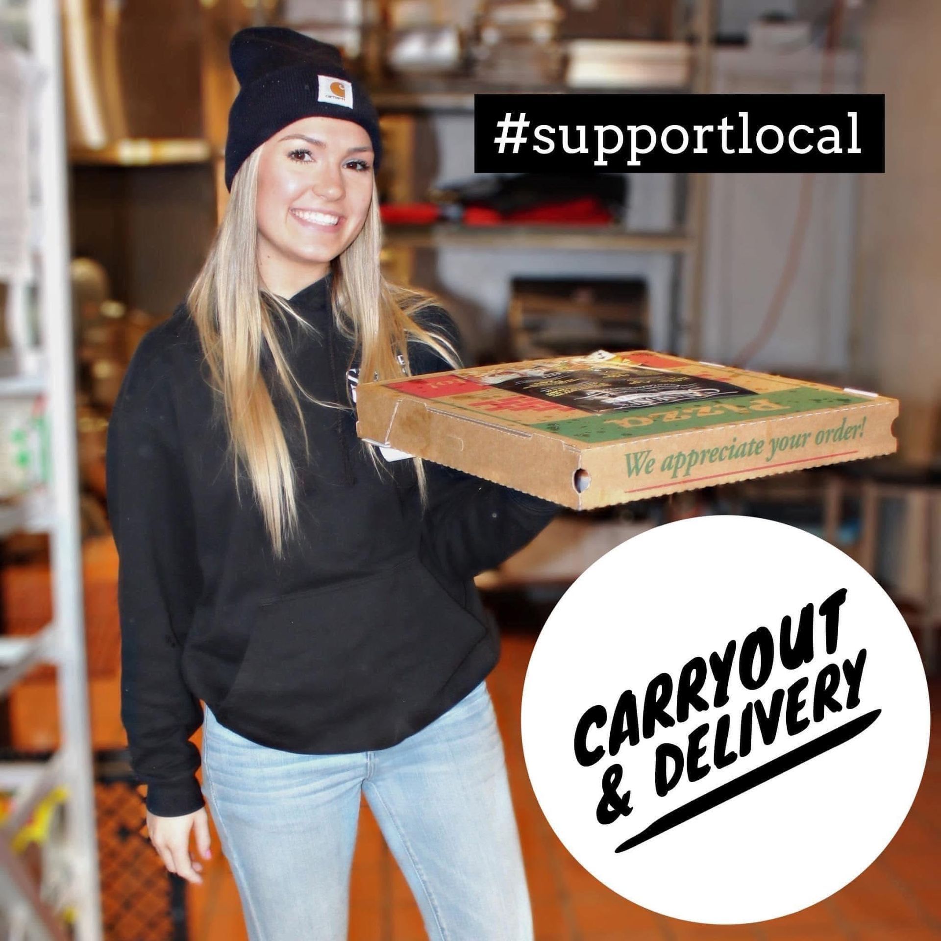 A woman is holding a box of pizza