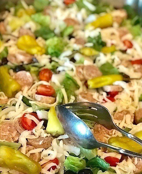 A close up of a salad with a fork and spoon in it.