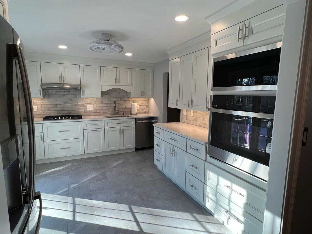 White kitchen with stainless steel appliances and light gray flooring.