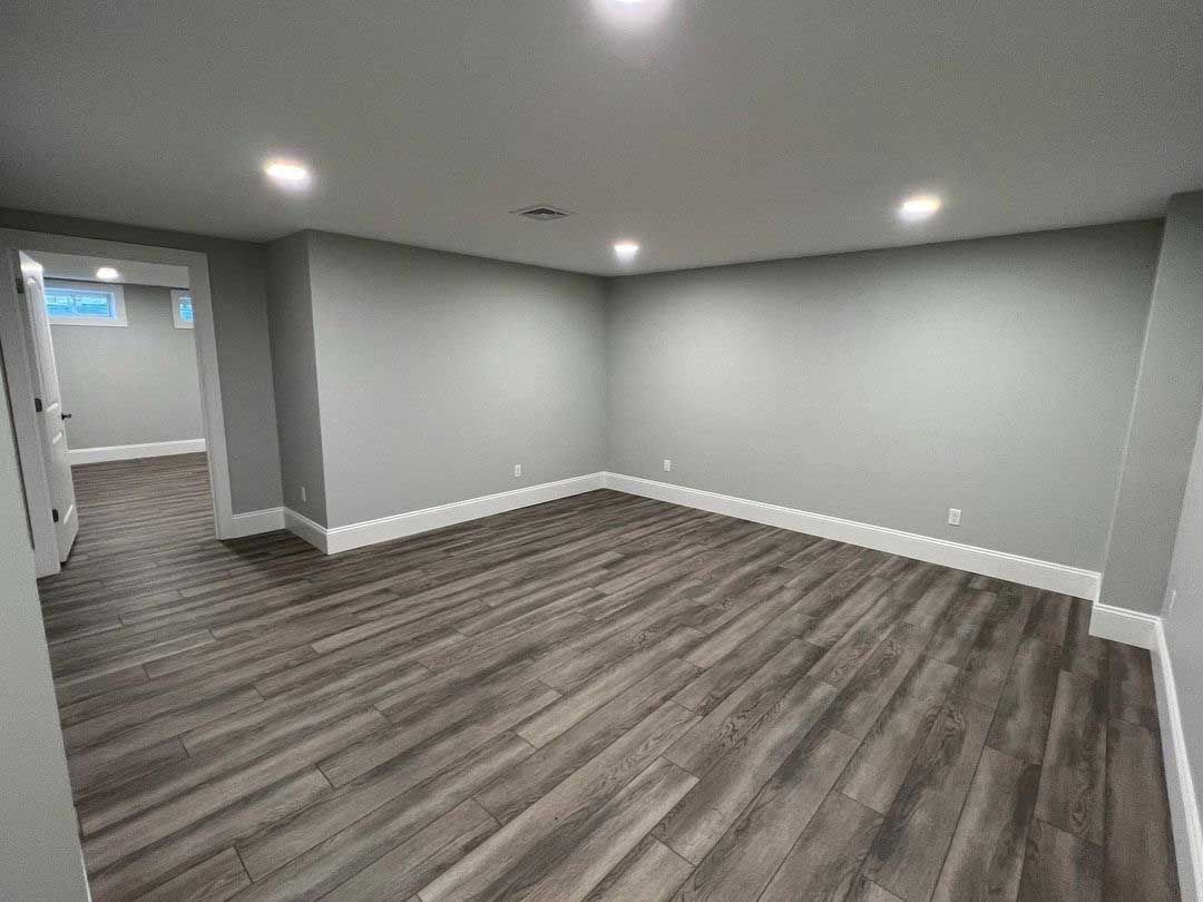 Empty room with gray walls, wood-look flooring, recessed lighting, and white trim.