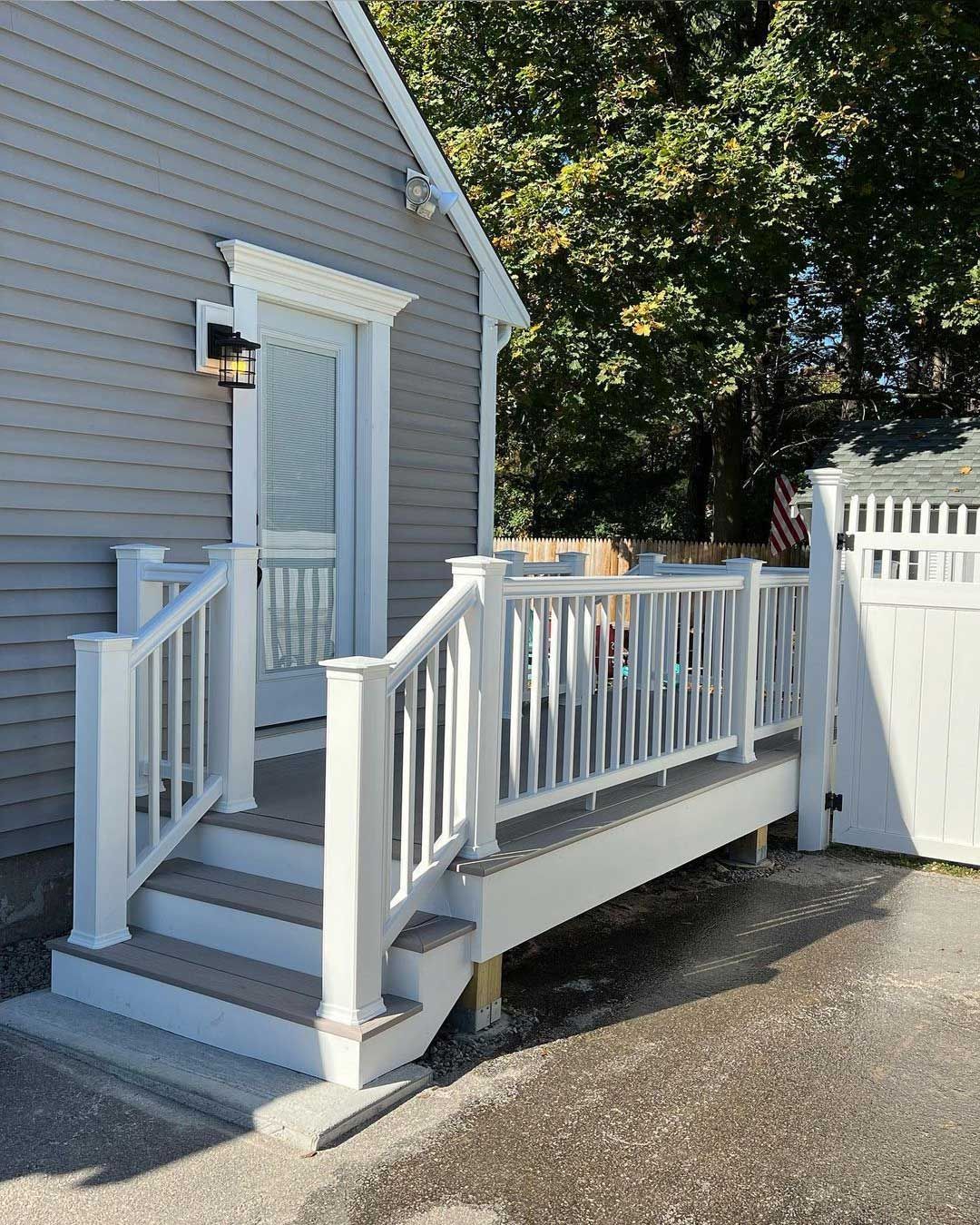 White ramp and steps leading to a gray house entrance with a screen door.