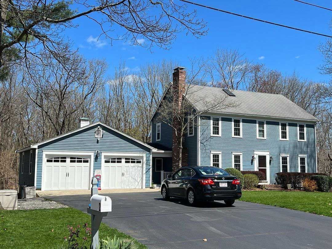 Two-story blue house with a garage. A car is parked in the driveway.