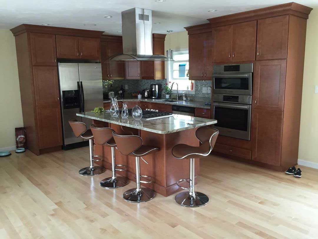 Modern kitchen with brown cabinets, stainless steel appliances, and a central island with bar stools.