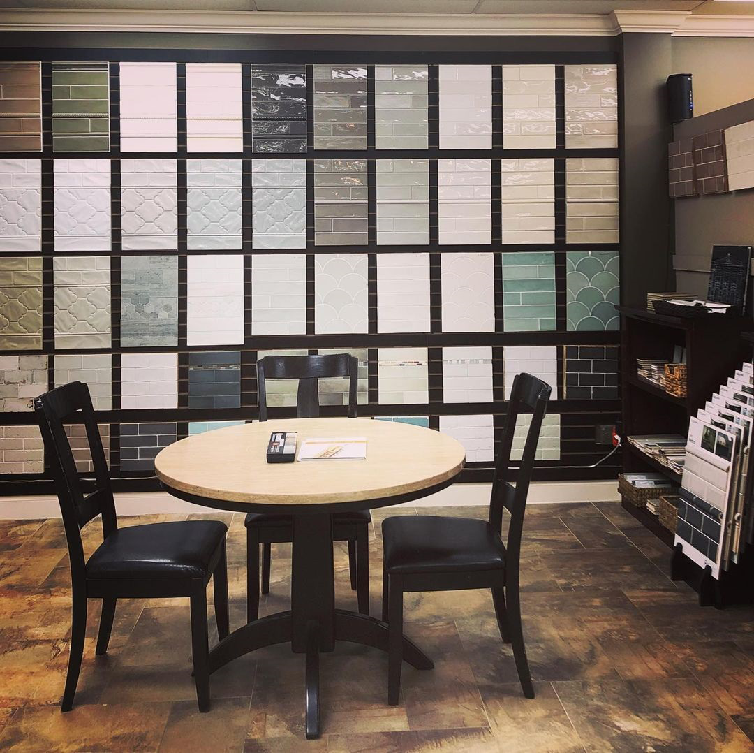 Small café interior with a round table, two chairs, and a wall of menu or tile samples.