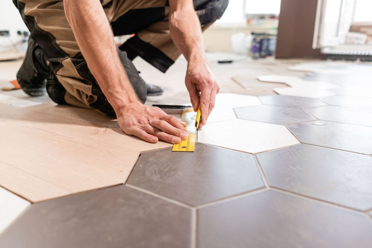 Person kneeling, installing hexagon tiles on floor, using spacer.