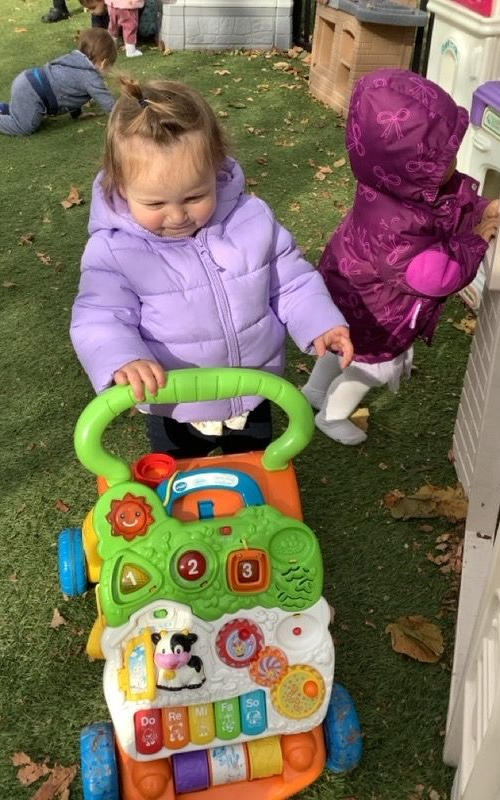 Children in costumes gather around a table, possibly baking or crafting, in a classroom.