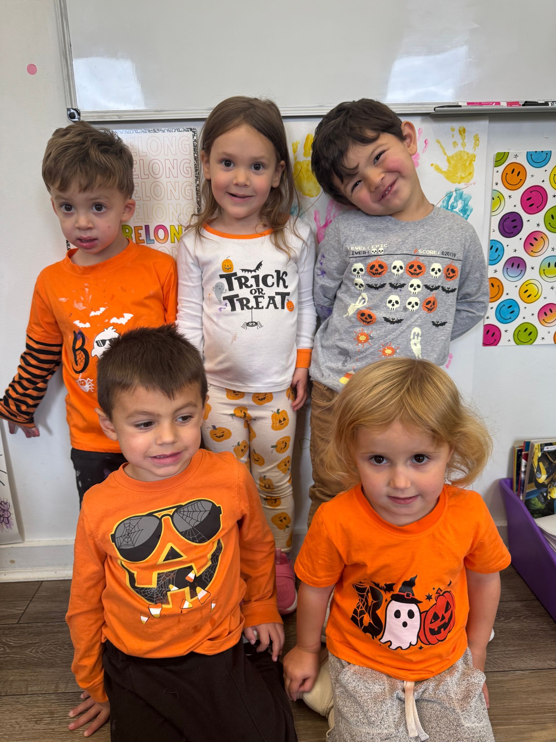 Two young girls holding hands, smiling in a colorful room with a rug. One has