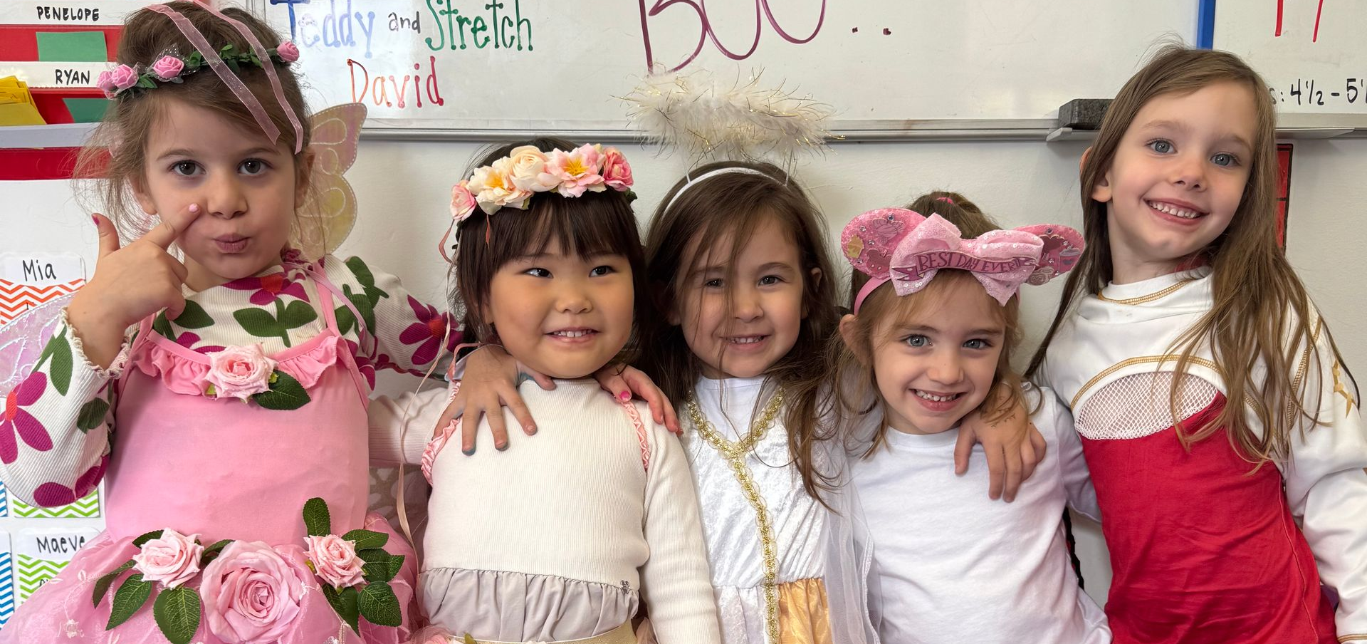Three young children in costumes, including a firefighter, in a grassy area.