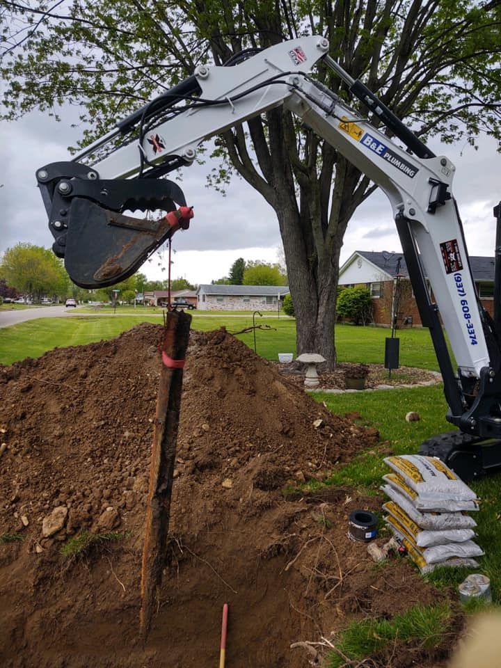Bobcat excavator removing a wooden post from a yard.