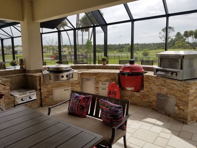 Outdoor patio with grill stations, red smoker, bench seating, and a view of a green golf course