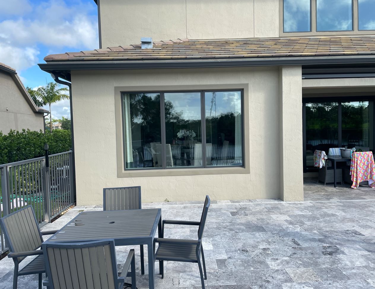 Backyard patio with gray table and chairs beside a house and large sliding window