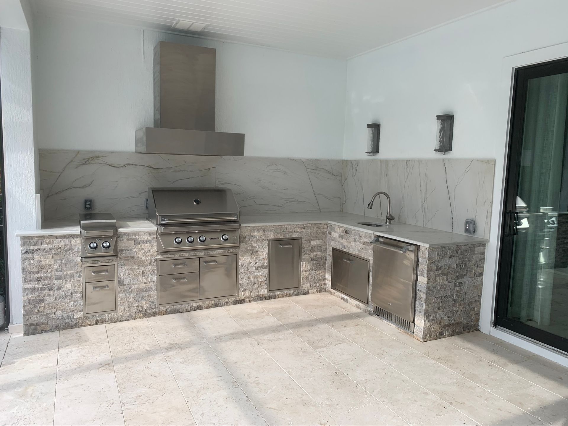 Outdoor patio with built-in stainless steel grill and stone countertop kitchen