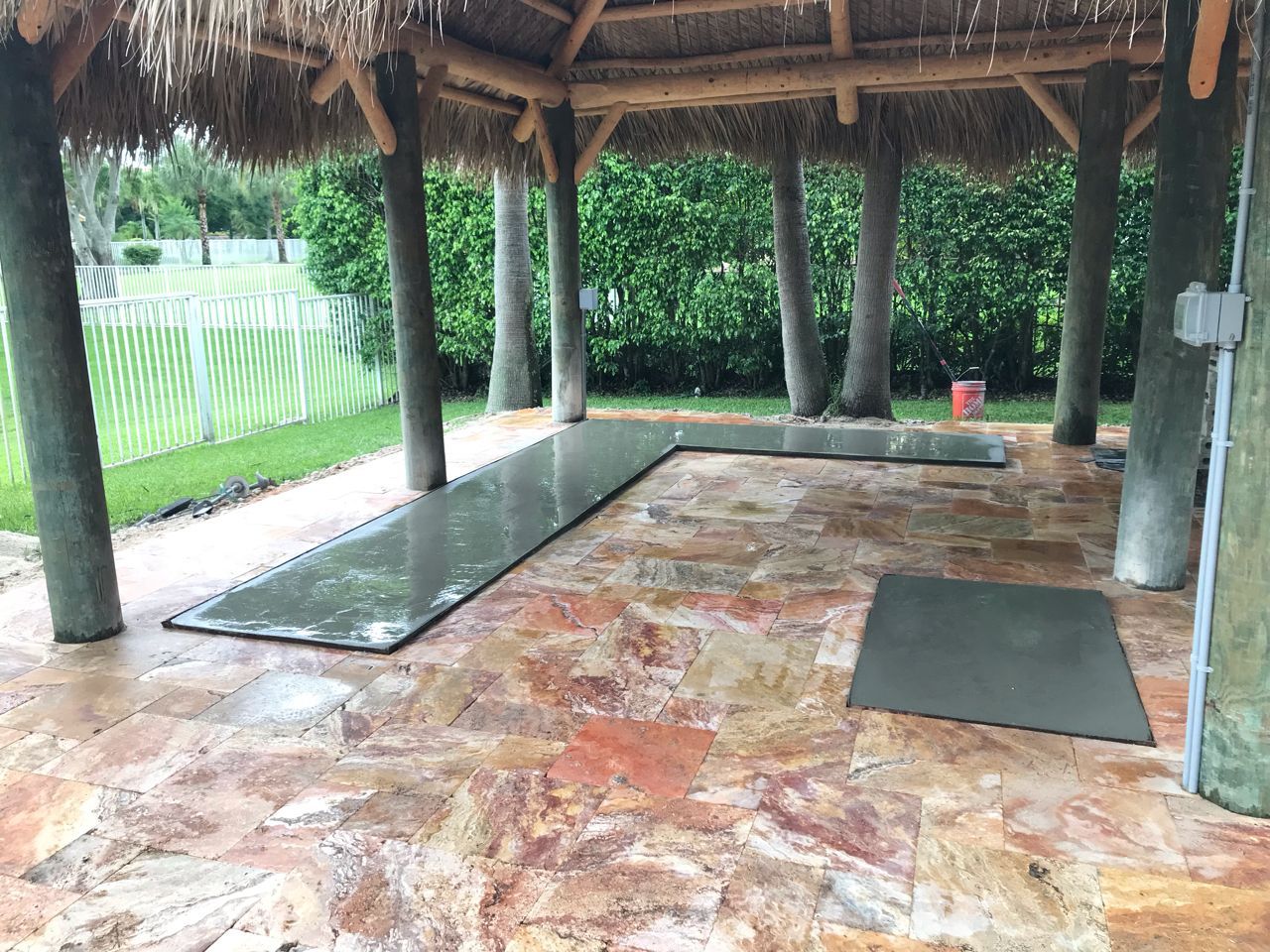 Thatched outdoor pavilion with stone floor, benches, and a view of greenery outside