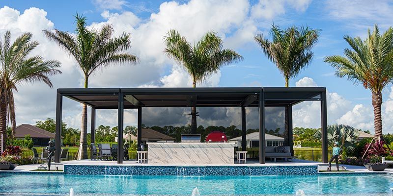 Luxury poolside cabana with palm trees and turquoise water under a cloudy sky