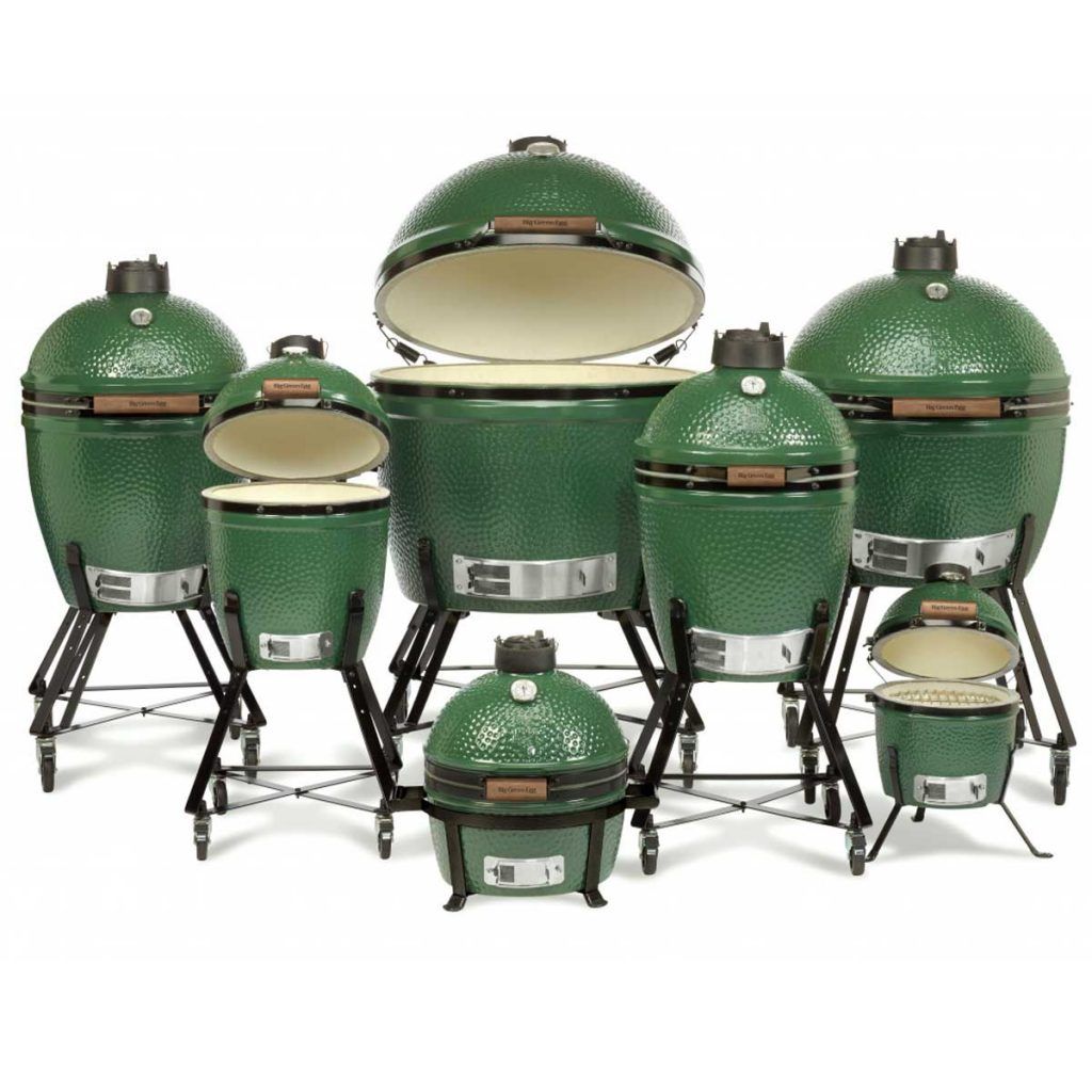 Assorted green ceramic kamado grills of various sizes, displayed on black stands against a white background