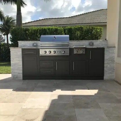 Outdoor built-in stainless steel grill and dark cabinets on a patio under a covered patio roof