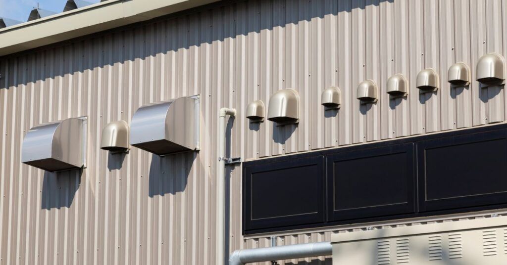 Exterior wall with metal vents and rows of small lights above a dark storefront sign