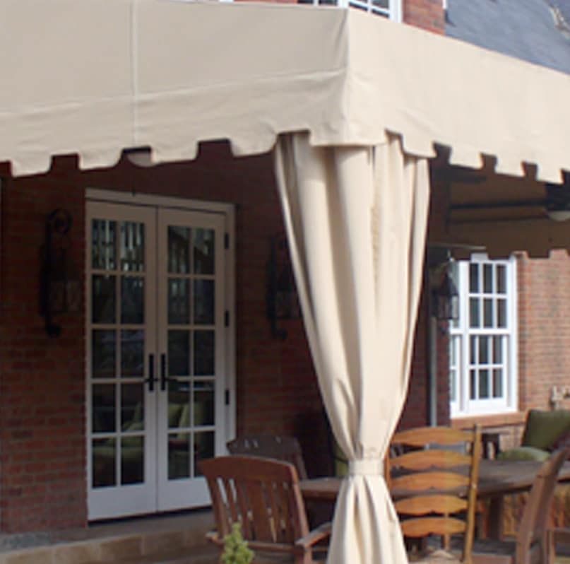 Patio with beige awning, brick wall, French doors, and outdoor seating